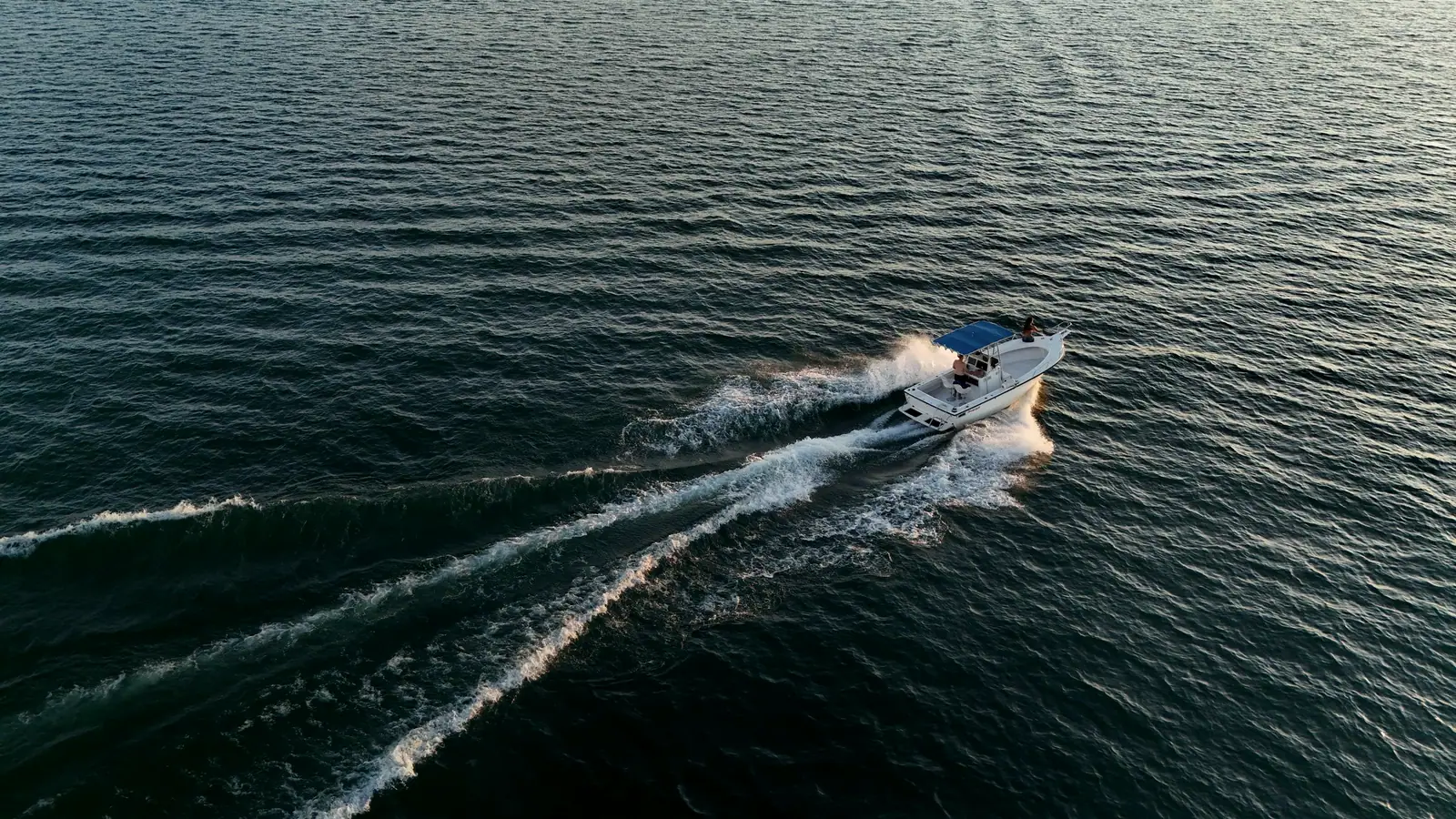 A boat cutting a wake across dark water