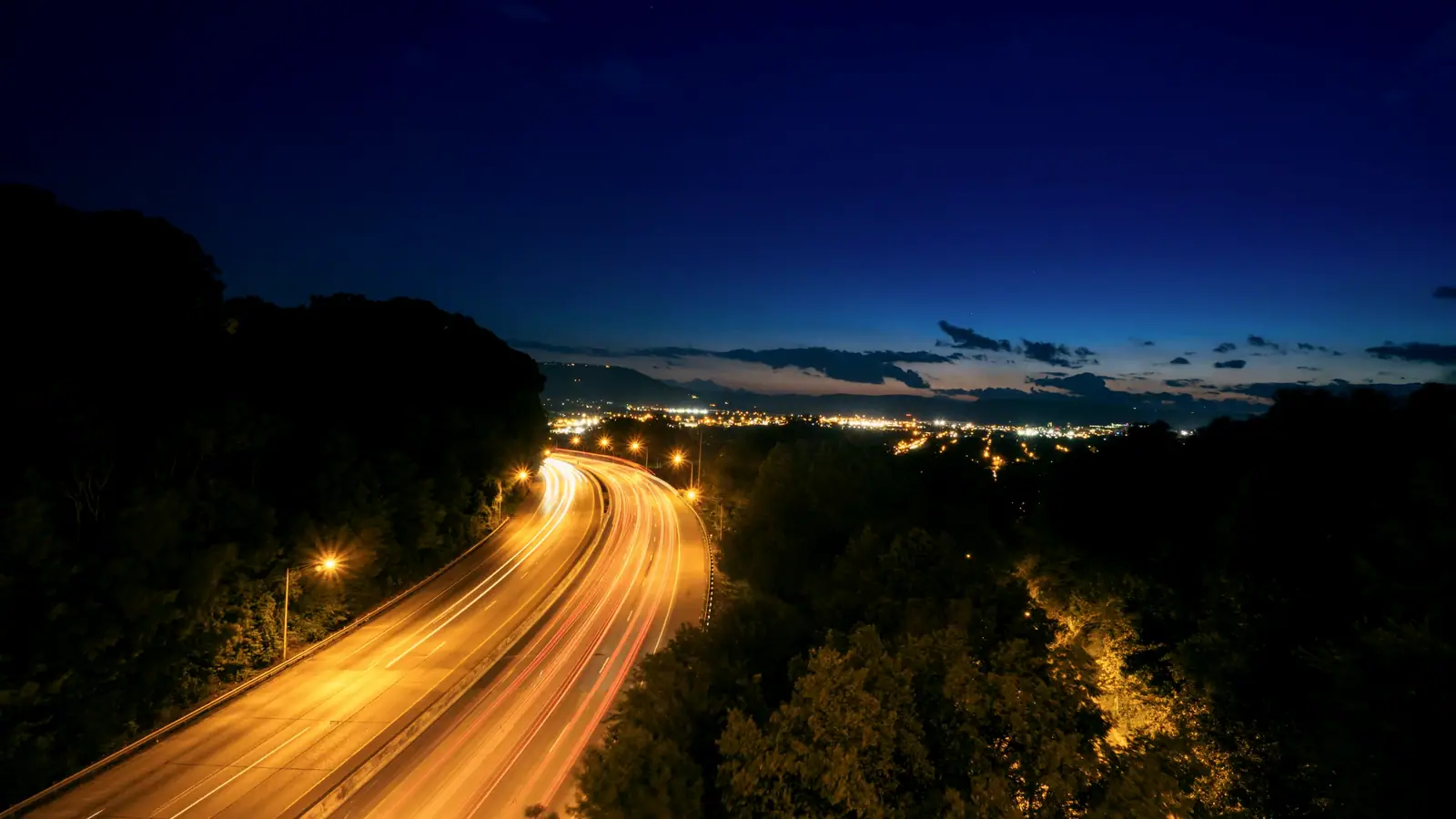 Traînées lumineuses vers la ville, à l'heure bleue